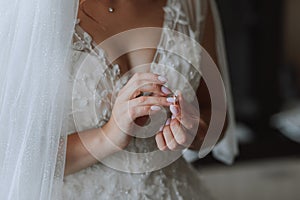 Wedding details. The bride is dressed in a white elegant dress, holding her wedding ring