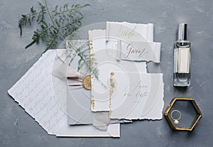 Wedding details flat lay. Wedding invitation and scroll paper. Bottle with fragrance. Ring box. Simple bouquet