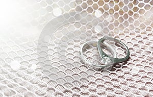 Wedding diamond rings on white fabric bokeh background