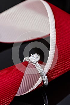 Wedding diamonds ring on black background with red ribbon