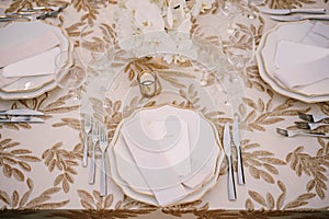 Wedding dinner table reception. Delicate creamy pastel tones of tablecloths and plates on table, three forks left and