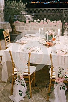 Wedding dinner table reception. Draping brown chairs Chiavari Tiffany with white cloth to floor, decoration with rose