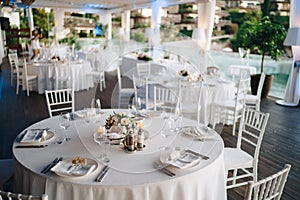 Wedding dinner table reception. Round banquet table with white tablecloth and white Chiavari chairs. Wedding under the