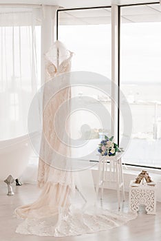 Wedding dress of the bride. The bride`s dress hangs on a hanger near the window