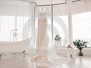 Wedding dress of the bride. The bride`s dress hangs on a hanger next to the bathroom