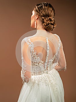 Wedding dress closeup. Rear view with tender french lace, long sleeves, white fabric-covered buttons.