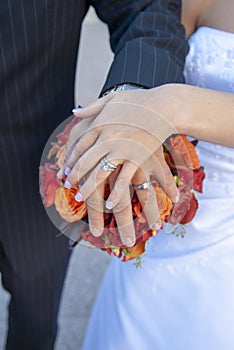 Bride and grooms hands, rings and bouquet.