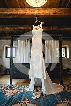 Wedding dress hanging in a rustical hotel room photo