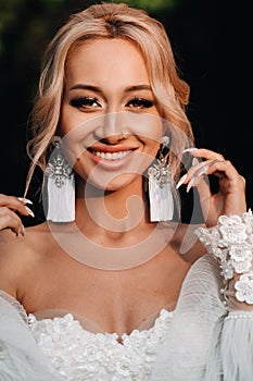 Wedding earrings on a female hand, she takes the earrings, the bride fees, morning bride, white dress, wear earrings