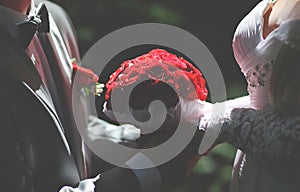 Wedding elegant couple bride and groom holding beautiful red bouquet flowers, closeup photo and soft light