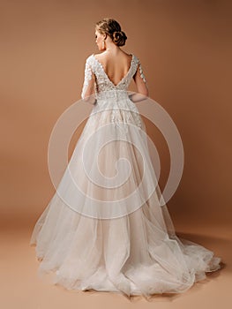 Wedding fashion. Elegant brunette model in backless ivory lace wedding dress with long sleeves.