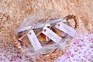 Wedding favours orange jam in small glass jars thank you guest gift in brown wicker basket