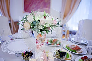 Wedding floristry. Beautiful lush bouquet on the table in restaurant. Table served food and snacks