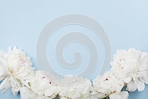 Wedding frame made of beautiful white peony flowers on blue pastel table. Top view and flat lay style.