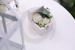 Wedding gold rings decorated with flowers on a white background in a wooden box on the table for a wedding ceremony