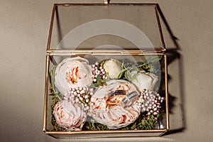 wedding gold rings in a glass box lie next to a wedding bouquet with austom. aesthetics and details of the wedding