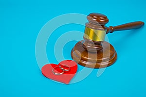 Wedding gold rings on the heart and the judge`s gavel on blue background. Concept divorce, break off otnasheniya.