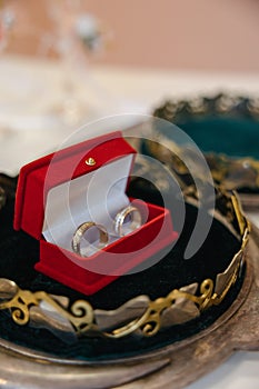 Wedding golden rings bands in a red velvet box in the center of a golden crown.