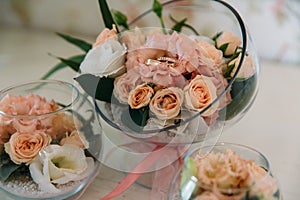 Wedding golden rings decorated with flowers on white background in big glass