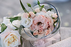 Wedding golden rings decorated with flowers on white background in big glass