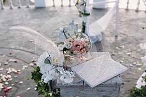 Wedding golden rings decorated with flowers on white background in big glass