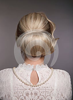 Wedding hairstyle. Portrait of Retro woman with shiny wavy bundle hair, feather in head. Back view of Elegant lady posing isolated