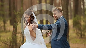 Wedding. Happy couple in a forest in the fresh air. Elegant groom behind bride. In the hands of a beautiful bouquet of
