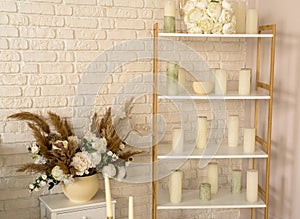 Wedding interior of room. On shelf lies a white bouquet of bride flowers, candles, glasses and shoes