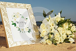 Wedding invitation and beautiful bouquet on sandy beach, closeup