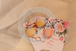 On the wedding invitation lying four pastry macaroons and wedding rings. Wedding .