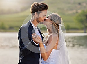 Wedding kiss, couple and lake with a bride feeling love, care and support from marriage together. Nature, happiness and