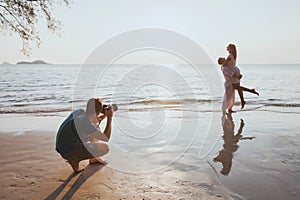 Wedding and lifestyle photographer taking photos of affectionate couple on the beach