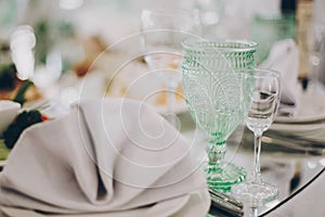 Wedding luxury table setting at reception in restaurant. Stylish glasses for wine, plate with napkin, cutlery and food on tables.