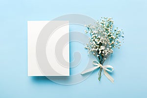 Wedding mockup with white paper list and flowers gypsophila on colored table top view flat lay. Blank greeting cards and