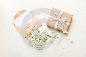Wedding mockup with white paper list and flowers gypsophila on colored table top view flat lay. Blank greeting cards and