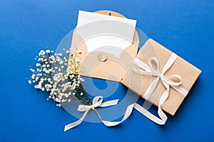 Wedding mockup with white paper list and flowers gypsophila on colored table top view flat lay. Blank greeting cards and