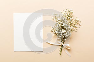 Wedding mockup with white paper list and flowers gypsophila on colored table top view flat lay. Blank greeting cards and