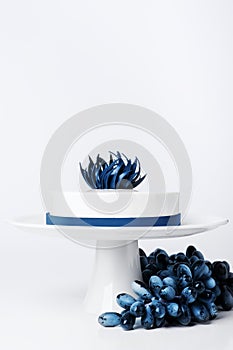 Wedding modern trendy white cake on cake stand isolated background with grape or berry set decorated blue trendy chocolate flower