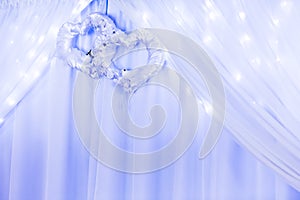 Wedding ornament with two hearts and curtain and lights.