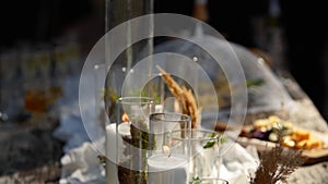 Wedding party banquet outdoors in forest. Dining table decorated in boho style with candles, white cloth, flowers