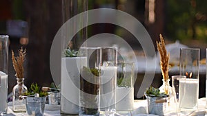 Wedding party banquet outdoors in forest. Dining table decorated in boho style with candles, white cloth, flowers