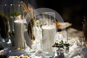 Wedding party banquet outdoors in forest. Dining table decorated in boho style with candles, white cloth, flowers