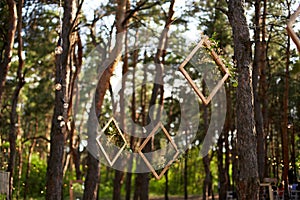 Wedding party banquet outdoors in pine forest. Dining tables, benches decorated in boho style with candles, flowers