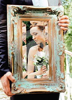 Wedding people concept, groom holding vintage mirror with bride reflection