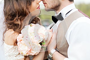 Wedding photo shooting. Bride and groom , holding hands of each other. Very close to each other. Closed eyes