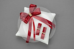 Wedding Pillow for Rings decorated with red ribbons.