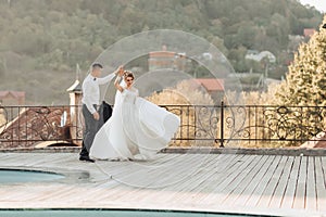 Wedding portrait. A groom in a black suit and a blonde bride dance a waltz