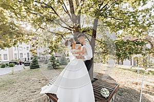 Wedding portrait. A groom in a black suit and a blonde bride in a dress and sneakers