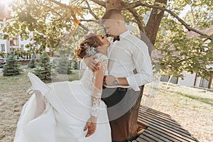 Wedding portrait. A groom in a black suit and a blonde bride in a dress and sneakers