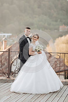 Wedding portrait. The groom in a black suit and the blonde bride are standing.